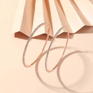Close-up of 8cm rose gold hoop earrings with sparkling white rhinestones on beige prop