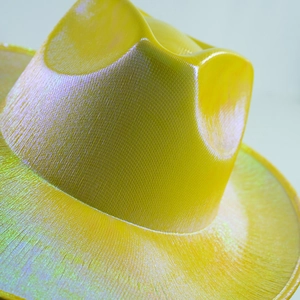 Macro texture of yellow laser holographic cowboy hat with shimmering pearlescent finish