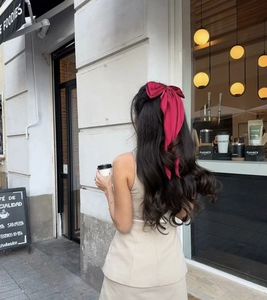 Detail of a large burgundy satin bow hair clip with long ribbons on half-up hairstyle