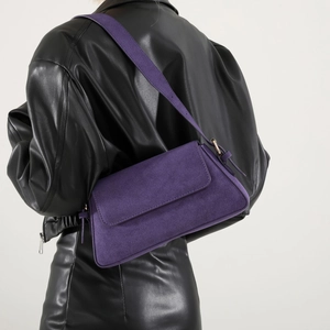 Detail of purple faux suede underarm bag with adjustable strap on leather jacket