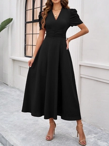 Close-up of black V-neck dress with puff sleeves and elegant pleated waist detail
