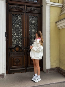 Photo en extérieur d'un sweat à capuche blanc oversize zippé porté par un mannequin