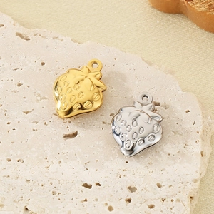 Macro detail of strawberry-shaped metal pendants in gold and silver finish with textures