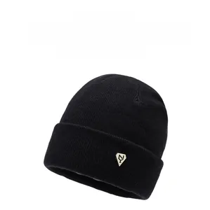 Detailed close-up of a black knit beanie with a silver metal NY emblem decoration