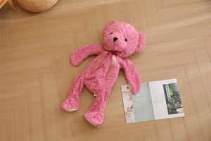 Detailed texture of pink rose plush teddy bear skin with decorative silk bow on wood floor