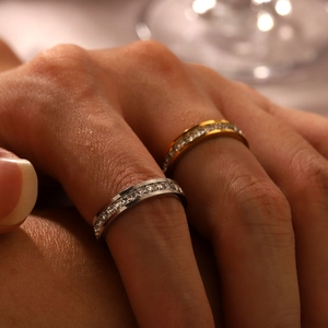Close-up of stacked gold and silver eternity rings with channel-set square zircon stones