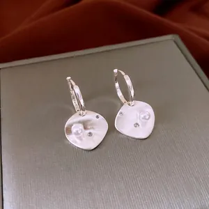 Modern brushed silver earrings with pearls and zircons on a jewelry display box