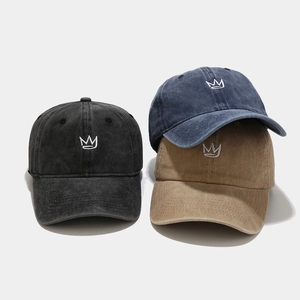 Close-up of three vintage washed cotton baseball caps with embroidered crown logos
