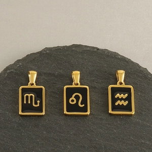 Detailed view of three 18k gold rectangular zodiac charms with black enamel inlay