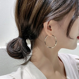 Close-up of model wearing irregular textured gold square earrings in a minimalist style