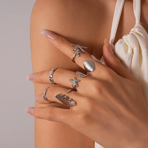 Close-up of silver sea star and shell geometric ring set on model fingers