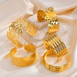 Set of gold wide cuff bracelets featuring coral cutout and hammered metal textures