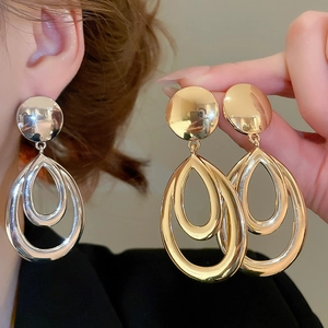 Détail des boucles d'oreilles gouttes d'or et d'argent poli au design géométrique creux