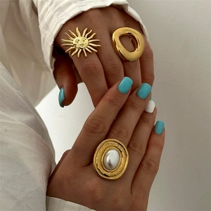 Retro gold ring set featuring sun god mask design and oval pearl on a model hand
