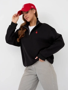 Black half-zip sweatshirt with red heart embroidery paired with a stylish red baseball cap