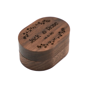 Detailed view of an oval walnut wood ring box with custom Jack & Rose floral engraving