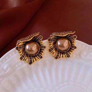 Detailed close-up of vintage gold shell earrings with champagne pearls and rhinestones
