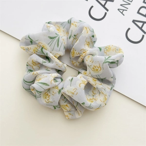 Close-up of floral chiffon scrunchie with blue background and yellow flower pattern
