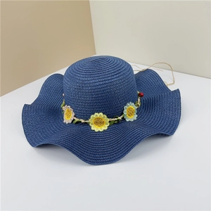 Détail d'un chapeau de paille bleu marine avec broderies tournesols et bord ondulé