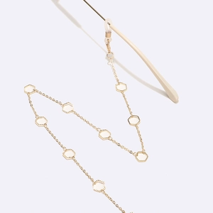 Detail of gold eyewear chain with white hexagonal resin accents and anti-slip rubber loops