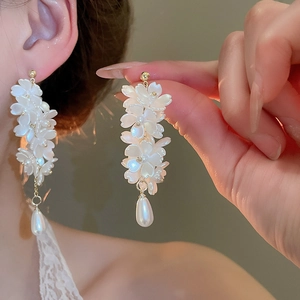 Gros plan de boucles d'oreilles fleurs à pompons blancs et pendentifs perles