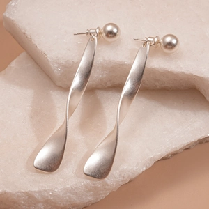 Macro detail of silver twisted metal earrings with matte texture on white stone