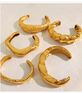Flat lay of five gold open cuff bracelets with diverse molten lava textures and metal finish