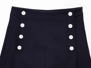 Dettaglio macro di minigonna blu navy con bottoni bianchi decorativi sulla vita