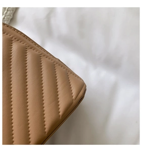 Detail view of the quilted stitching and textured synthetic leather on light brown bag