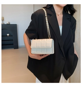 Detailed view of a white quilted crossbody bag with a luxury gold chain strap
