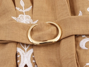 Close-up of khaki blouse with white floral embroidery and gold metal ring belt buckle