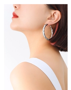 Close-up of a vintage silver twisted hoop earring on model showing modern metallic texture