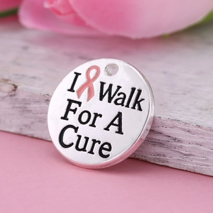 Silver I Walk For A Cure pendant with pink enamel ribbon on white wood background
