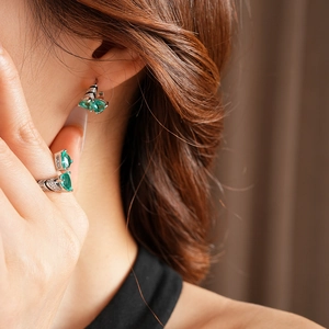 Detail of silver-tone jewelry set featuring pear-cut emerald stones on model