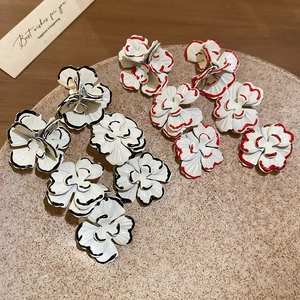 Close-up of floral tassel earrings with black and red hand-painted edges in a tray