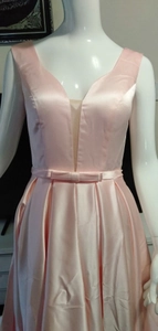 Detail view of pink satin evening gown featuring a deep V-neck and a matching bow waistband