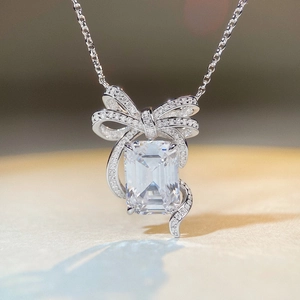 Close-up of bow necklace with emerald cut gemstone and pave-set diamonds in silver