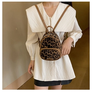Detailed back view of a mini leopard print backpack worn by a model in a modern interior