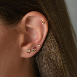 Close-up of 925 silver gold-plated cartilage studs with colorful zircons on ear