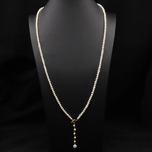 Long Y-shaped necklace with natural white pearls and gold buckle on a black background