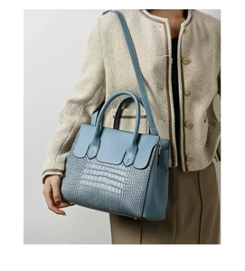 Detail of blue handbag featuring crocodile embossed leather pattern and gold hardware