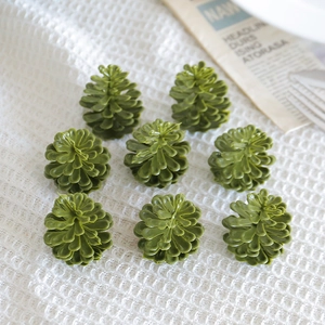 Flat lay of eight green plastic pine cones on a white waffle texture background cloth