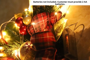 Close-up of Christmas teardrop swag with red plaid bow, ornaments and warm LED lights