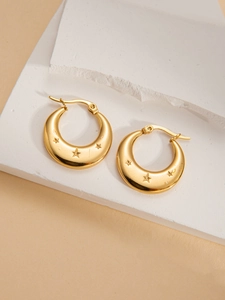 Detail view of gold crescent hoop earrings with engraved stars on a stone pedestal