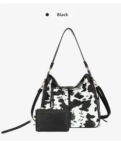 Detail view of cow print tote bag set with black small zipper pouch and strap