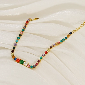 Bracciale regolabile in acciaio dorato con zirconi colorati su sfondo di seta bianca lucida