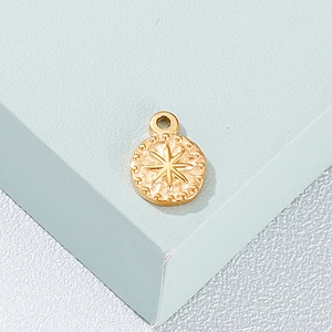 Close-up of golden stainless steel round pendant with star and dot embossed pattern