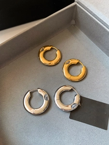 Detail view of chunky gold and silver hoop earrings with water-drop cubic zirconia stones