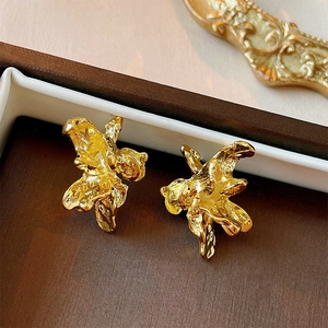 Detailed close-up of golden irregular textured flower stud earrings with a melted metallic finish