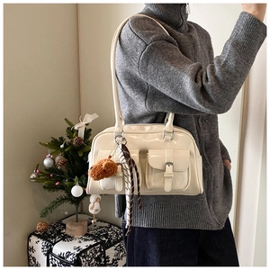 Detail of cream white pillow bag with front pockets and plush puppy charm accessory